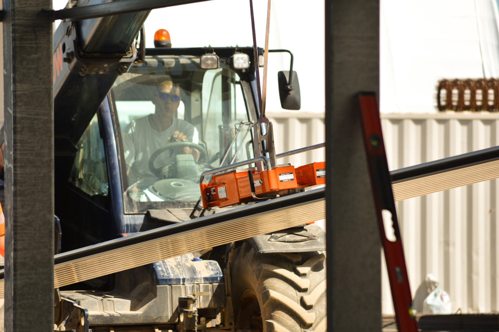 Heavy machinery constructing a large greenhouse facility on site